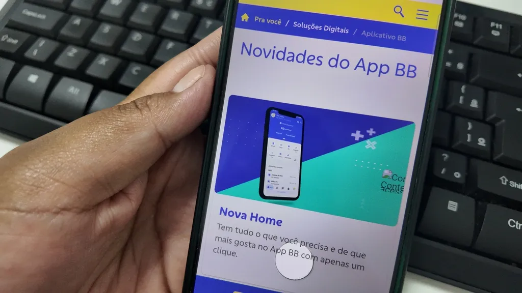 Imagem mostra celular com tela na página "Novidades do App BB". Atrás teclado na cor preta